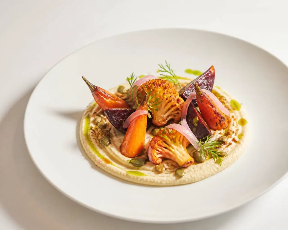 Entrée vegan gastronomique dressée comme un plat de restaurant, avec légumes rôtis, crème de légumineuses et herbes fraîches